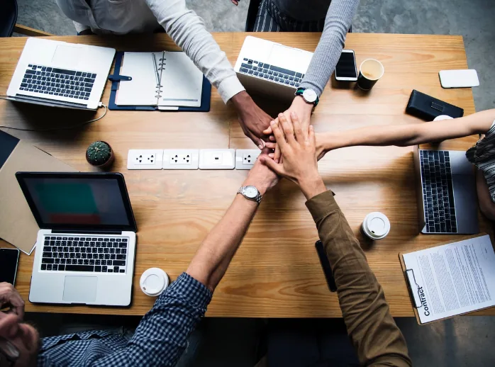 Equipe reunida colocando as mãos juntas sobre a mesa